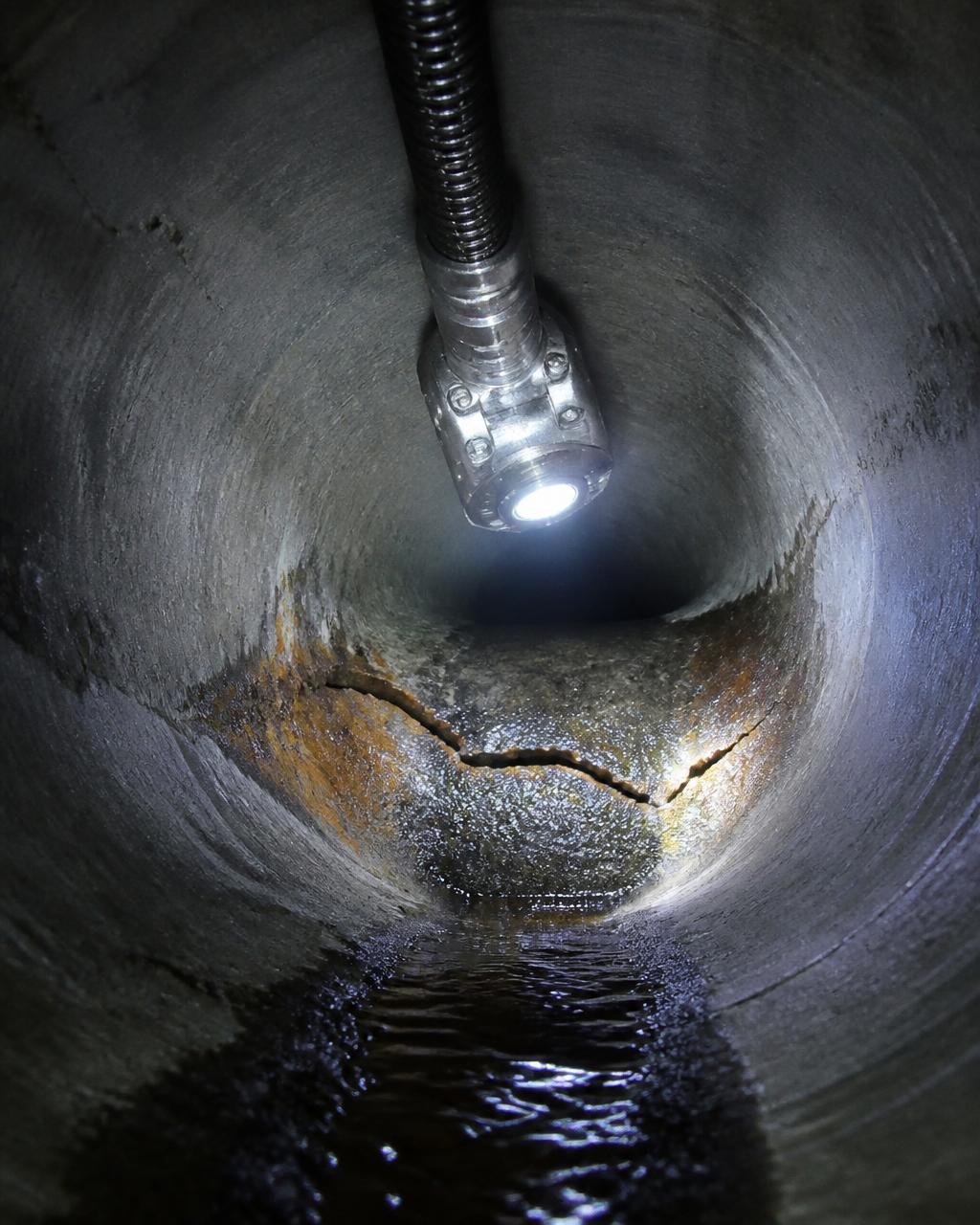 CCTV drain camera lighting up a cracked section of underground pipe